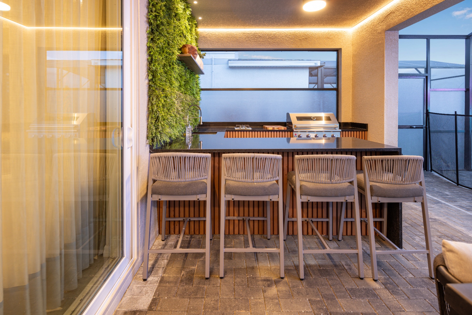 Área gourmet externa com bancada, churrasqueira e banquetas em projeto residencial